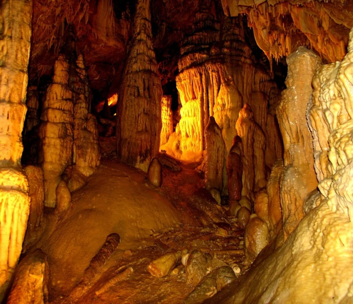 several stalate formations inside a cave with large boulders and trees