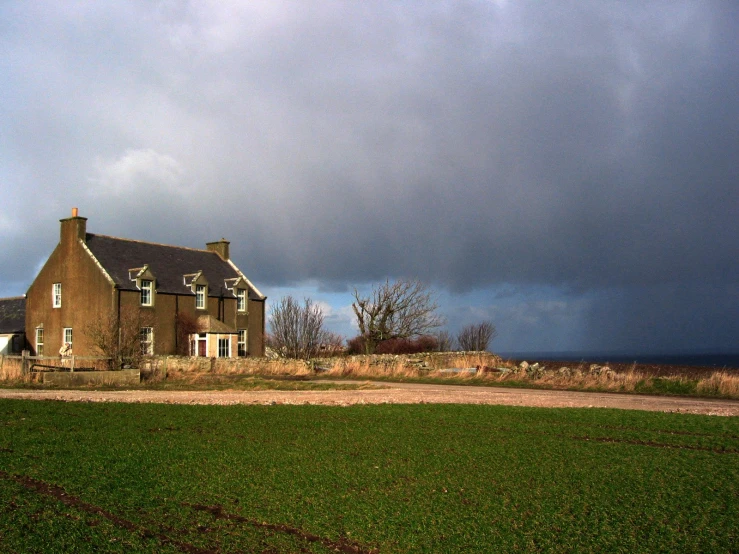 a large brown house with dark clouds in the sky