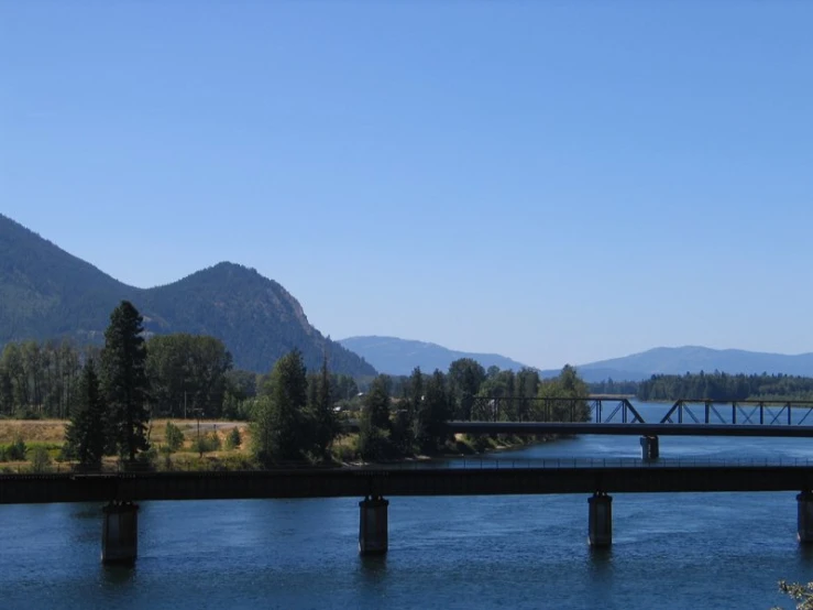 the mountains are seen in the distance and a bridge crosses the river