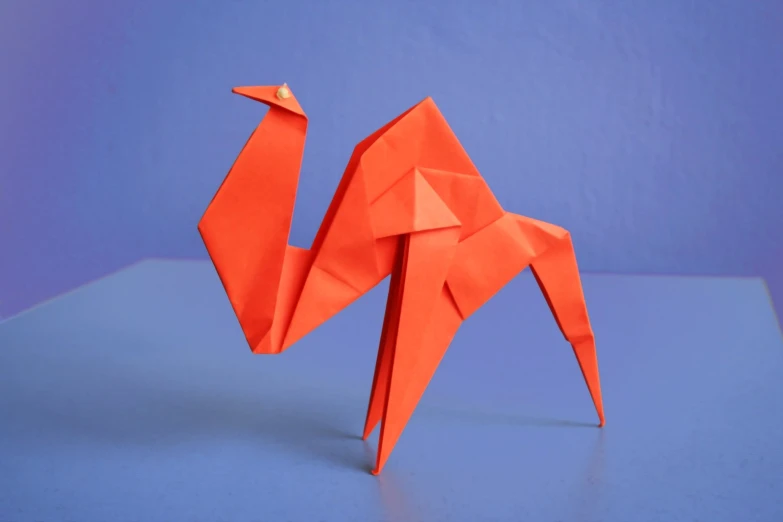an origami bird is posed against a bright blue background