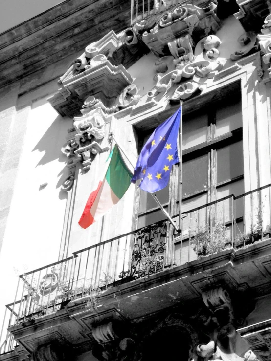 a multi - colored flag on a pole outside a building