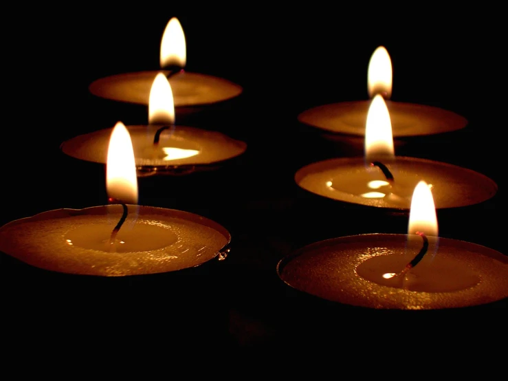 many lit candles are in a row on a black surface