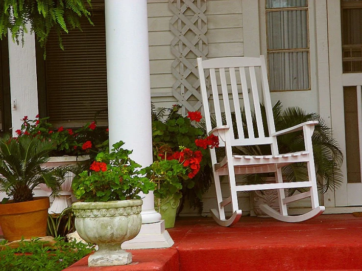 an outdoor white porch with rocking chair and potted flowers