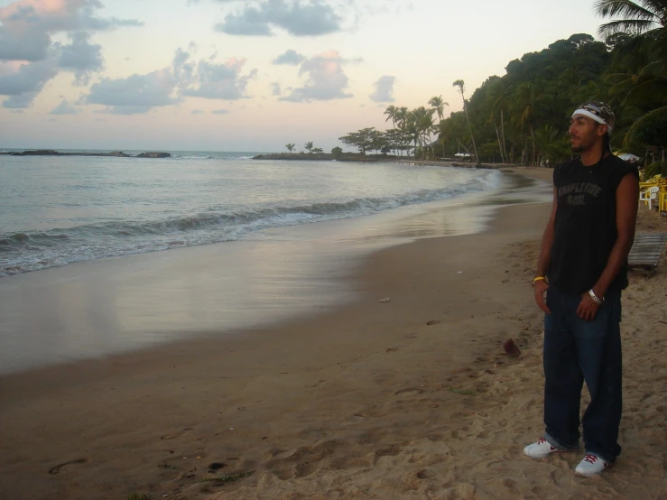 a young man standing on a beach next to the ocean