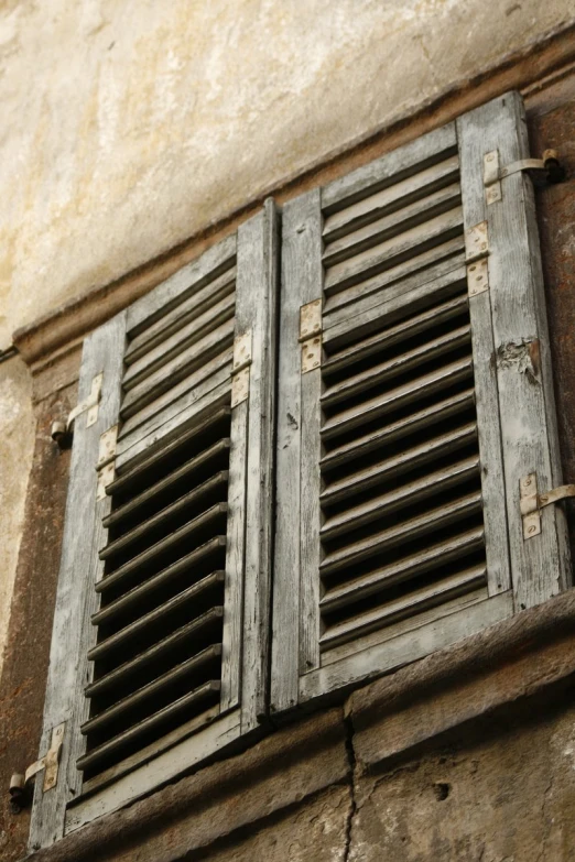 closed window in a brick wall with bars and blinds