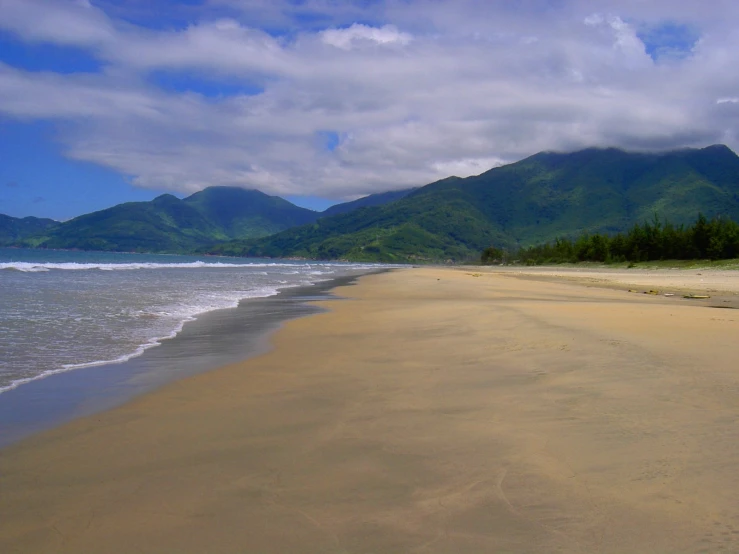 a view of the ocean, a mountain and cloudy skies