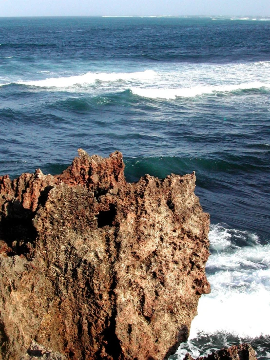 an ocean cliff with waves crashing and a clear sky