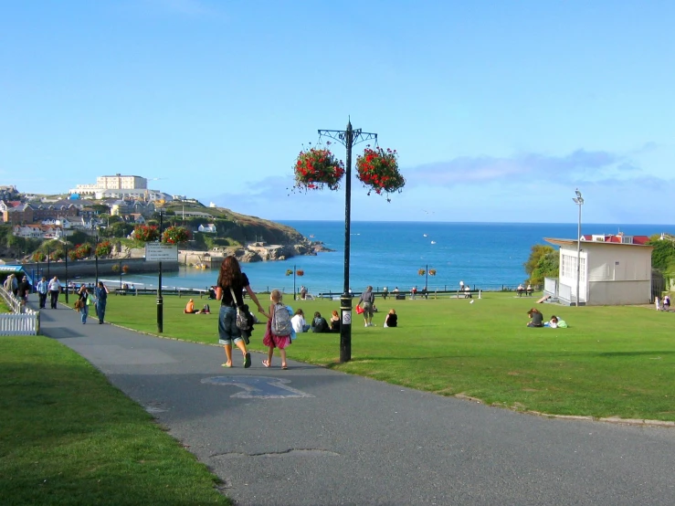 a couple of people are walking down a path by the ocean