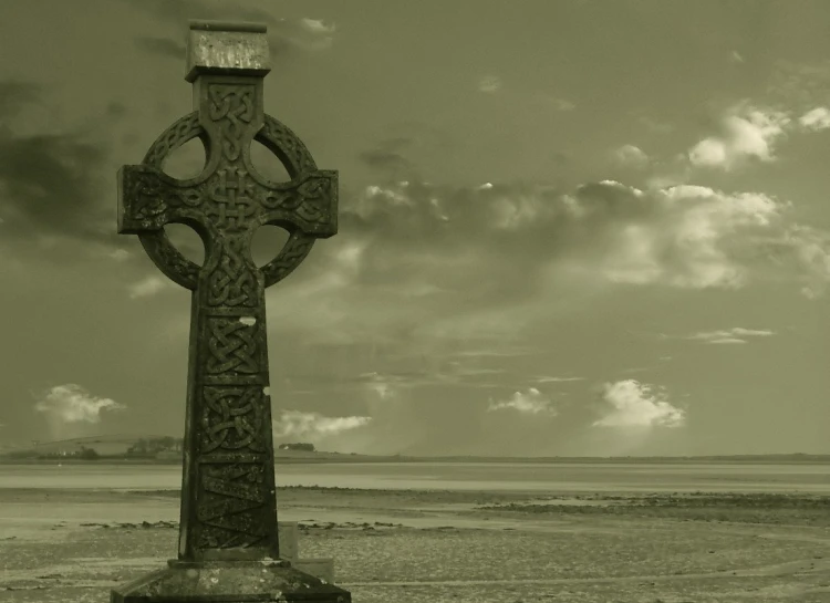an celtic cross on a beach near the ocean