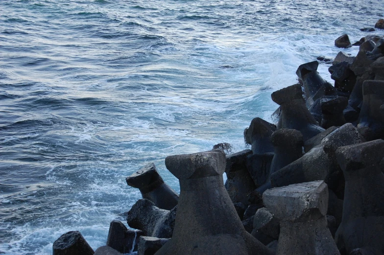 rocks at the edge of the ocean with a view of a body of water