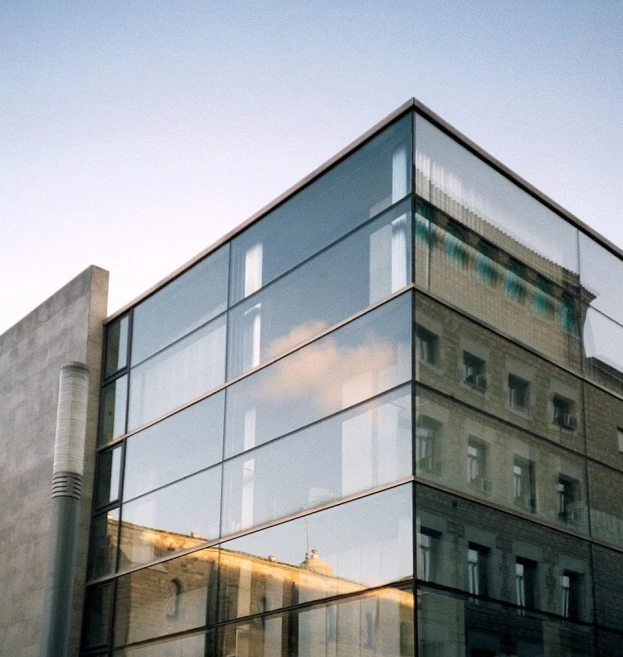 a glass building with a large reflection of clouds in the windows