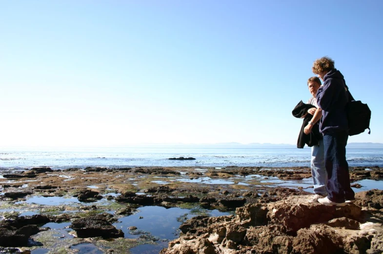 a person with a backpack standing near the ocean