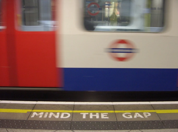 a subway with a sign on the platform reads mind the gap