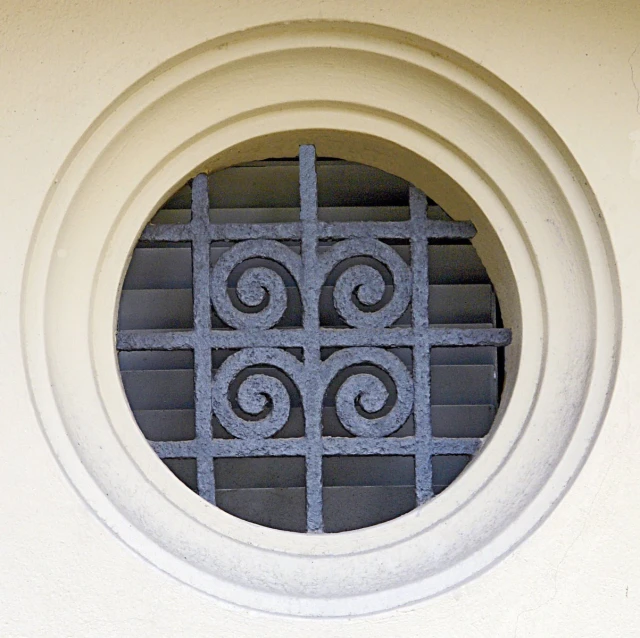 the top of an ornamental wall with round iron grilles