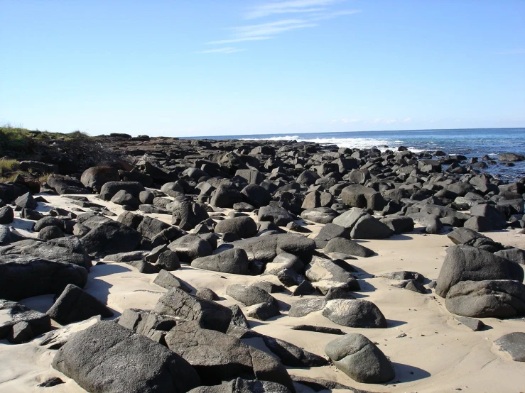 large rocks on a sandy shore with waves in the background