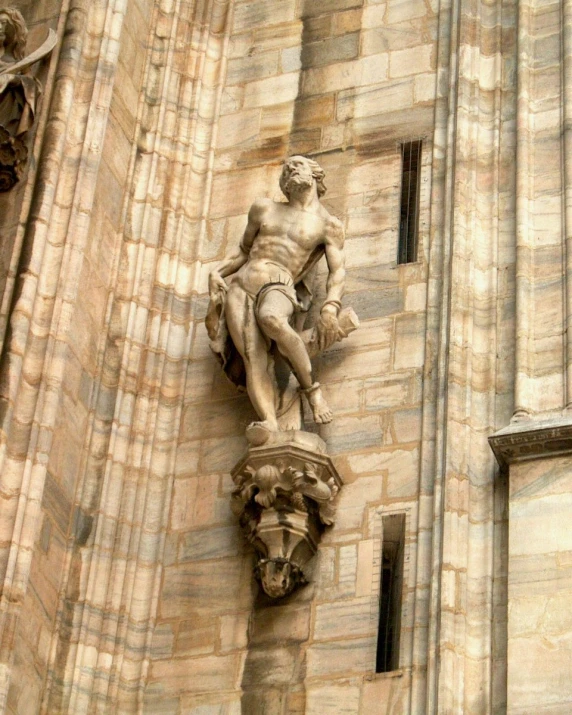 the statue is on a building wall above a decorative figure