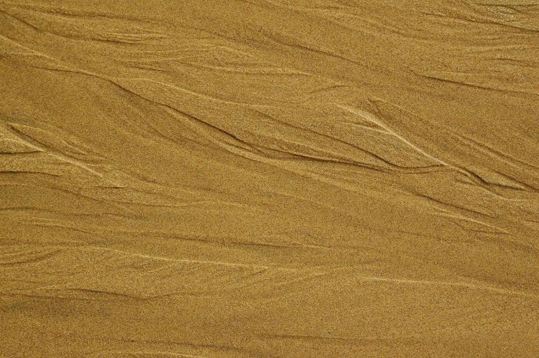 an airplane flies through the sand of a beach