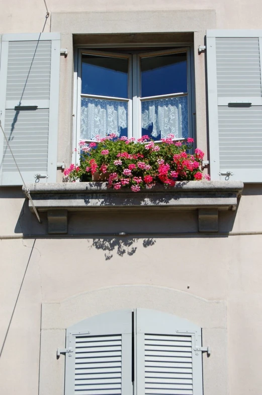 an old building with open shutters and a window with flowers