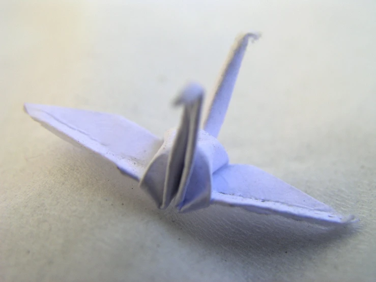 the folded origami boat is on the white surface