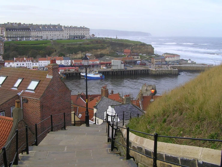 a view down some steps toward houses with buildings and a body of water in the background