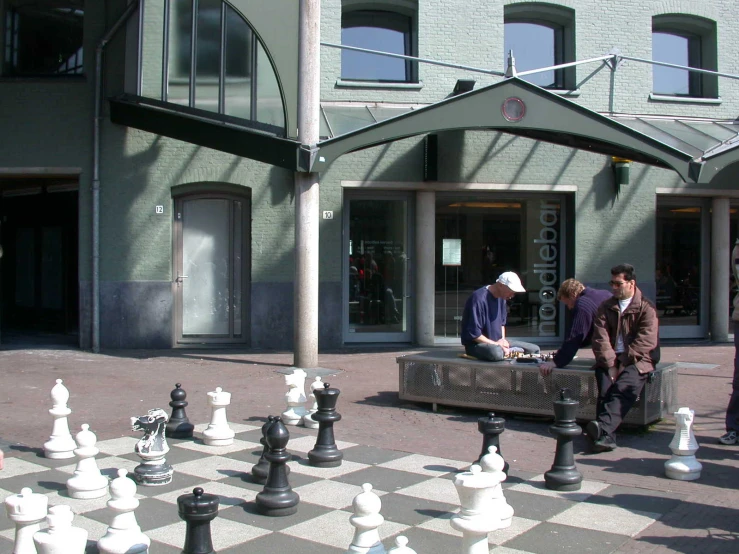 a man sits on a bench by chess set