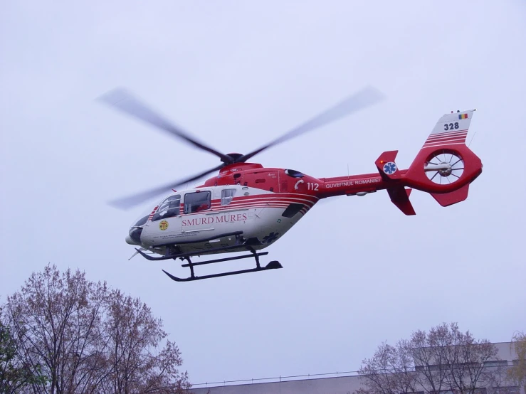 a red and white helicopter flies through the air