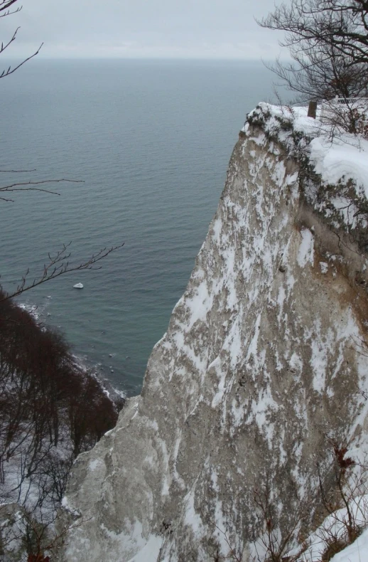 snow sits on top of a large cliff overlooking the ocean