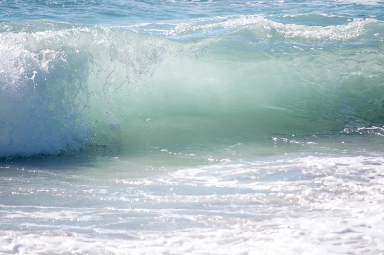 a wave is cresting over the ocean, about to crash