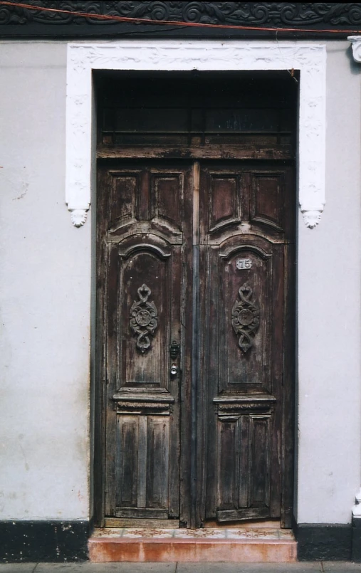 a doorway with two wooden double doors that have fancy ornaments above them