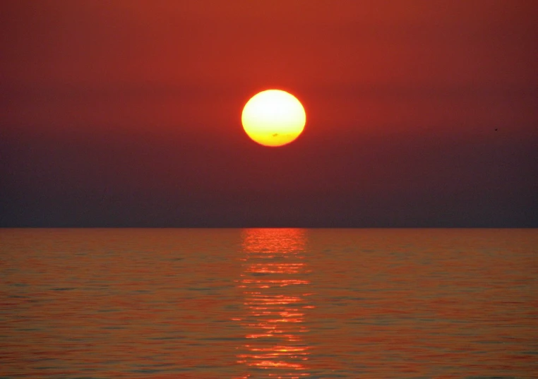 a large sunset seen over the ocean and the sun