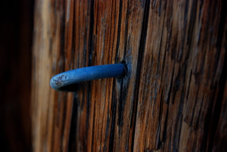 the wooden door is closed and the blue handle is metal