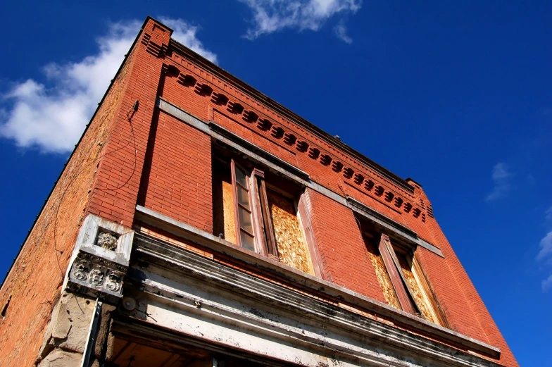 a very tall red brick building sitting under a cloudy blue sky