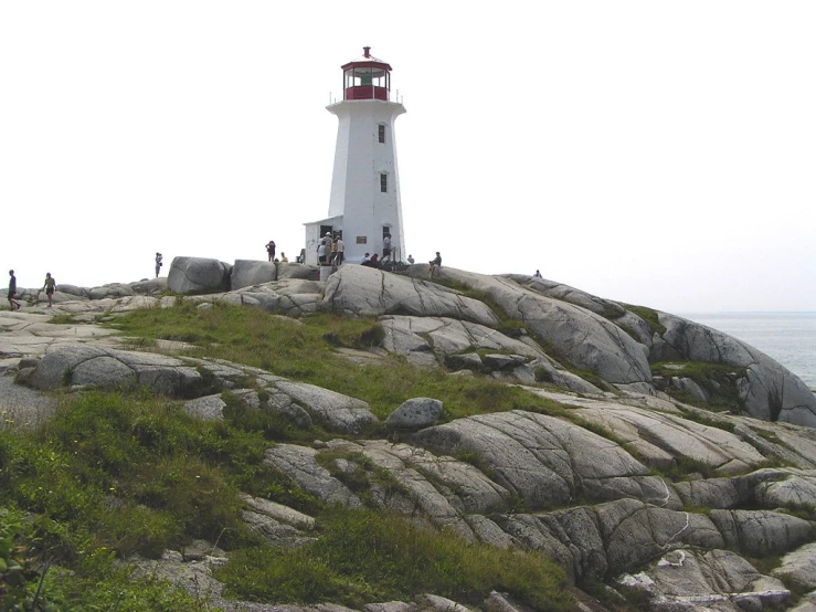 a white and red lighthouse stands on the rocks