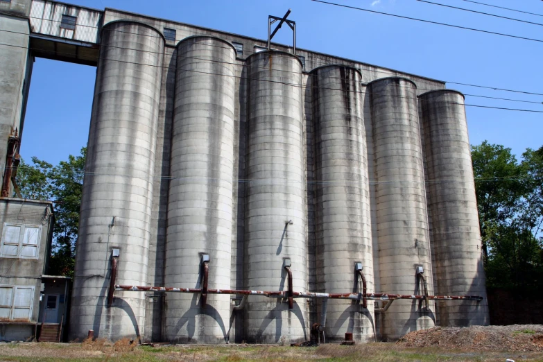 cement silos sitting in the grass beside an overpass