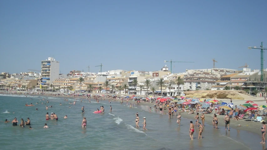 a crowded beach with people and umbrellas