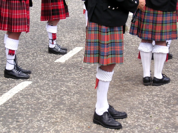 several men wearing kilts in rows on a street