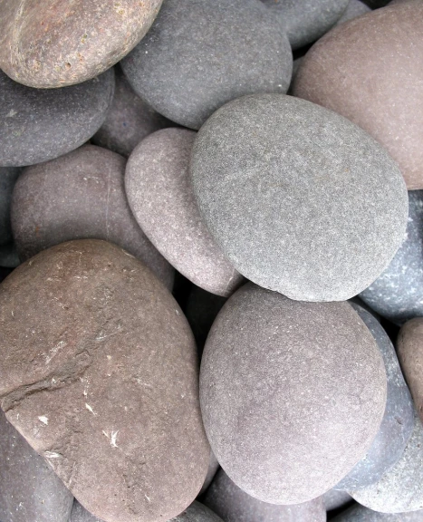many gray stones on a ground with black sand
