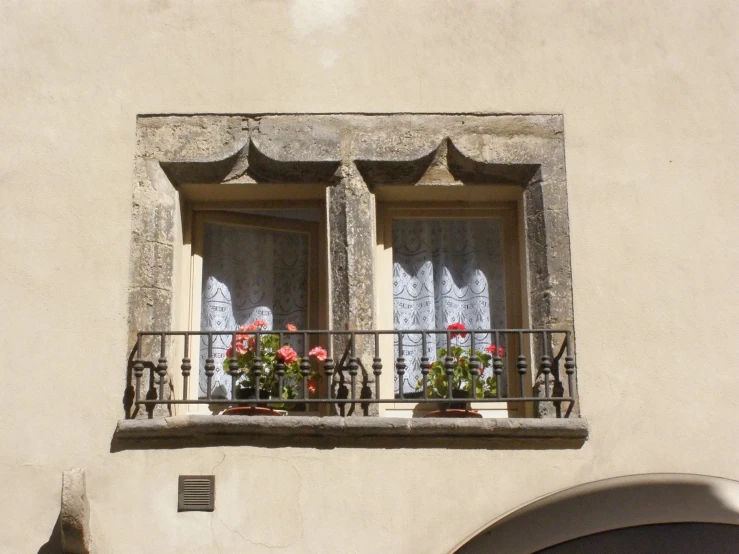 a balcony with flowers and curtains on the windowsill