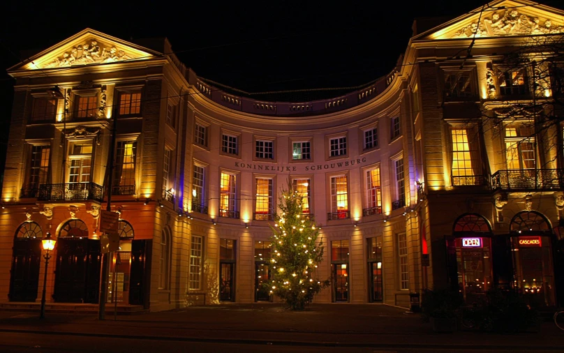 a large building with christmas lights and a christmas tree in front