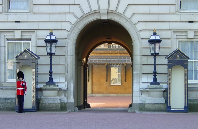 an archway on the front of a building has guard standing in front of it