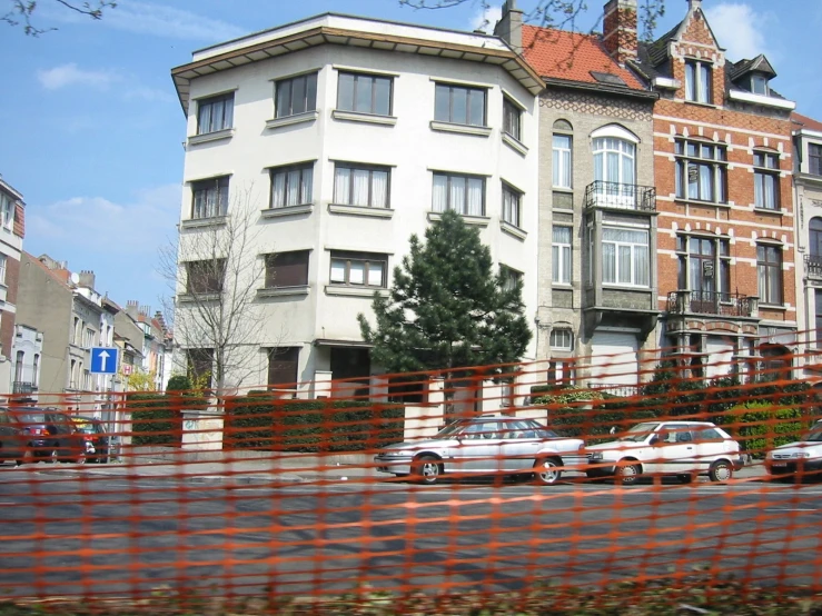 several cars are parked on the street near an apartment building