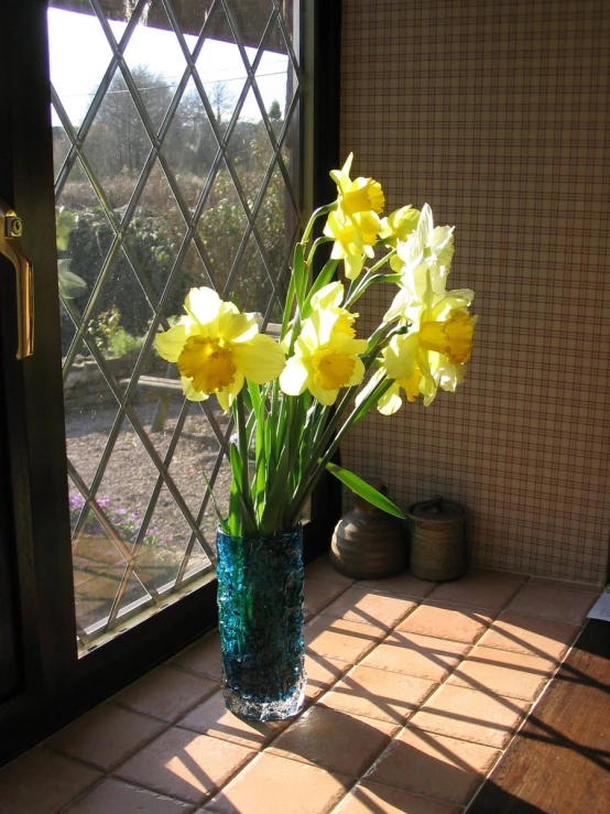 flowers in the vase sitting next to a glass door