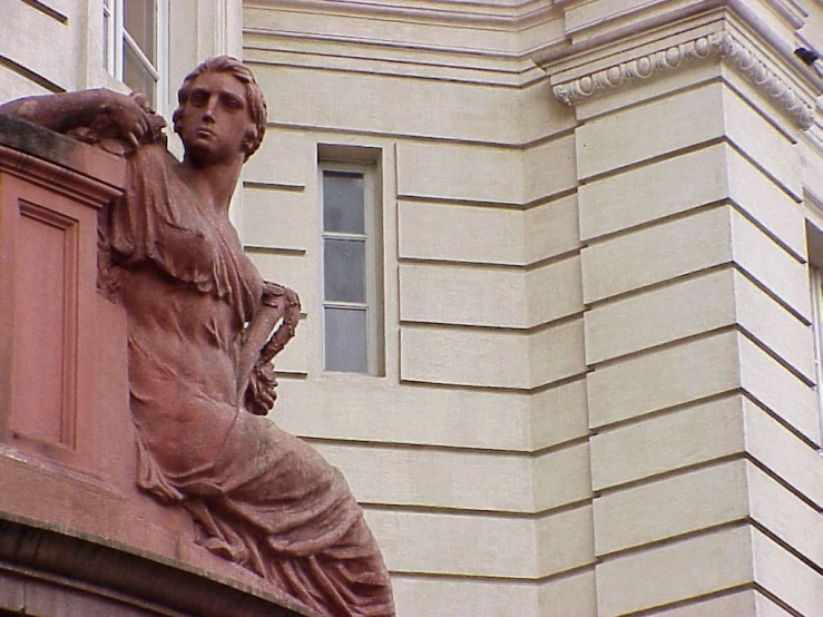 an ancient statue is standing next to a building