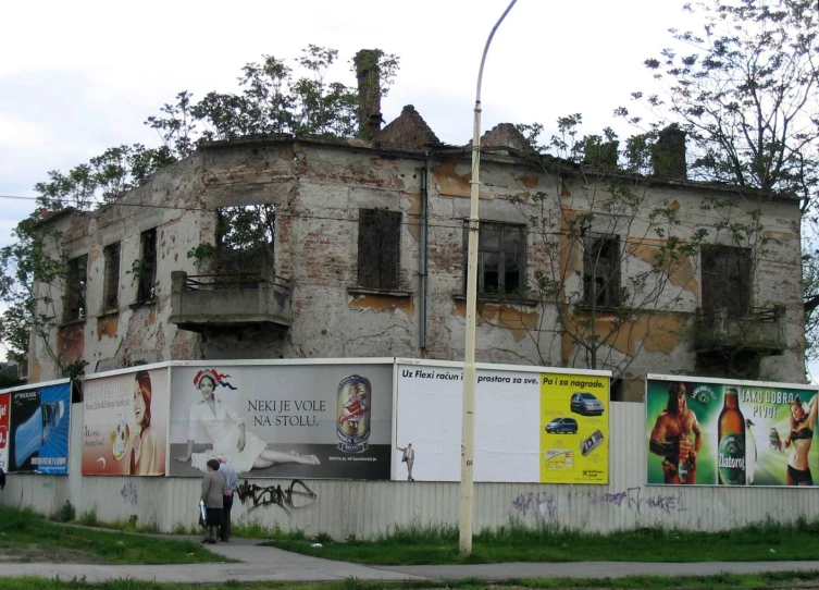an old brick building with posters on it and a person standing next to the building