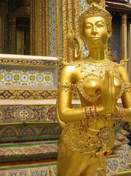 a golden statue in front of a decorative wall