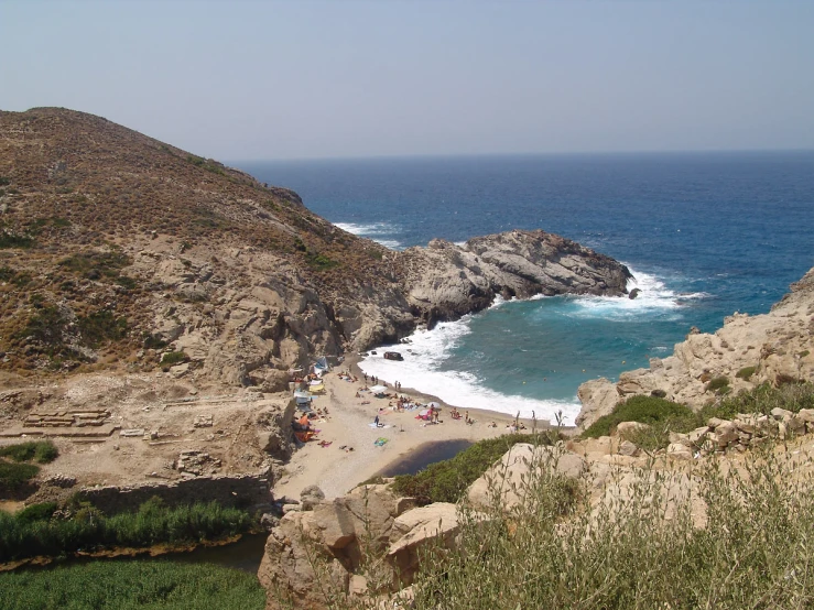 a beach area with many rocky cliffs, waves and blue sky