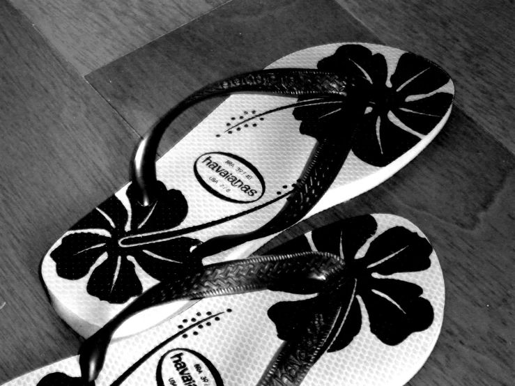 a pair of black and white flip flops with flowers on them