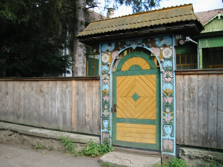 a large colorful wooden door stands by the wooden fence