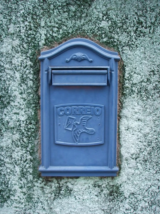 a cement wall with a blue mailbox on it
