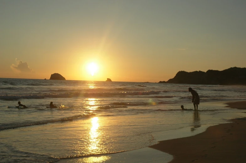 people are standing on the beach watching the sun go down